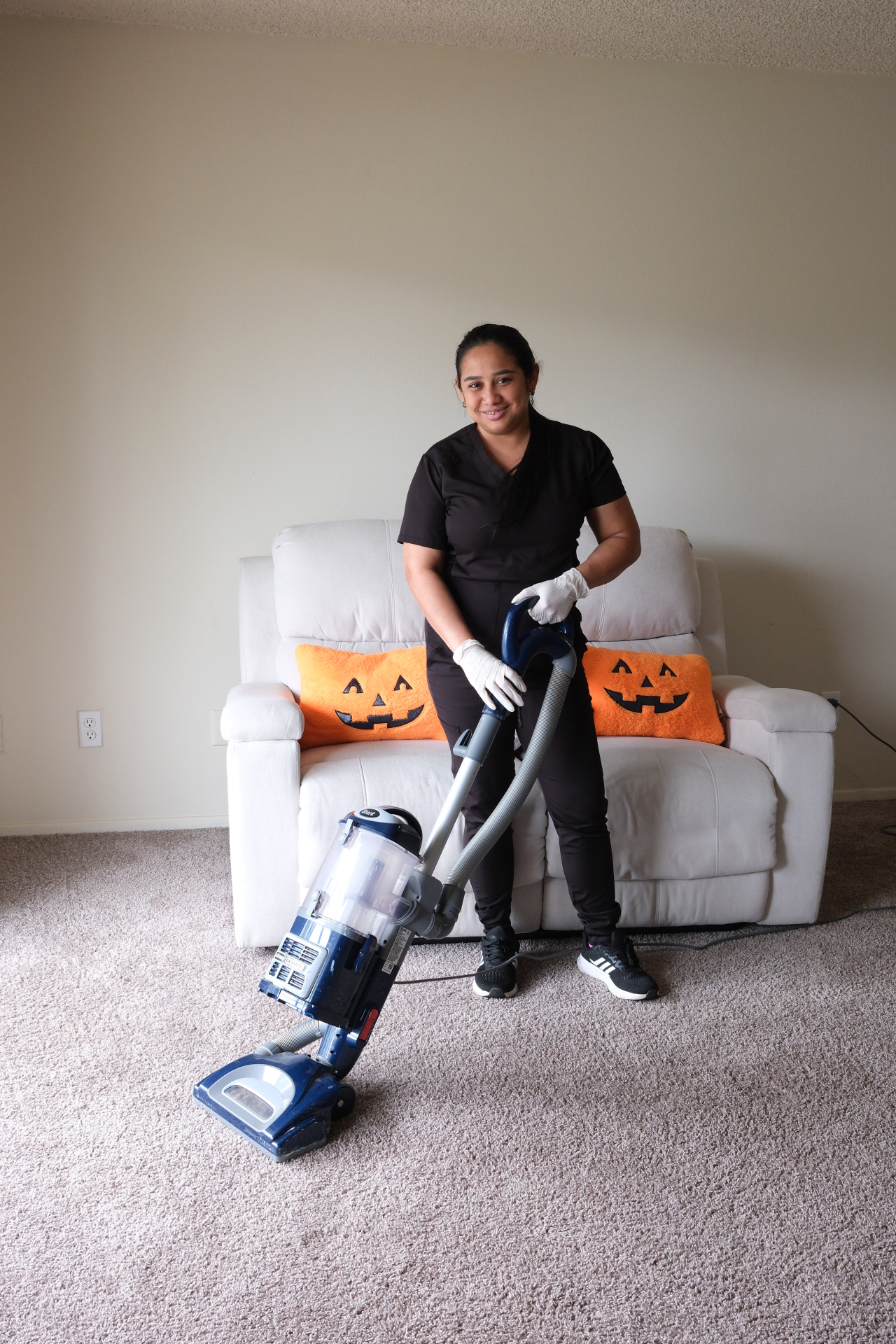Cleaner with vacuum smiling in living room